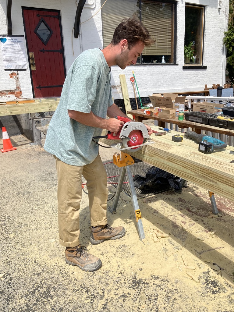 A man building a wooden medical ramp for someone's home.