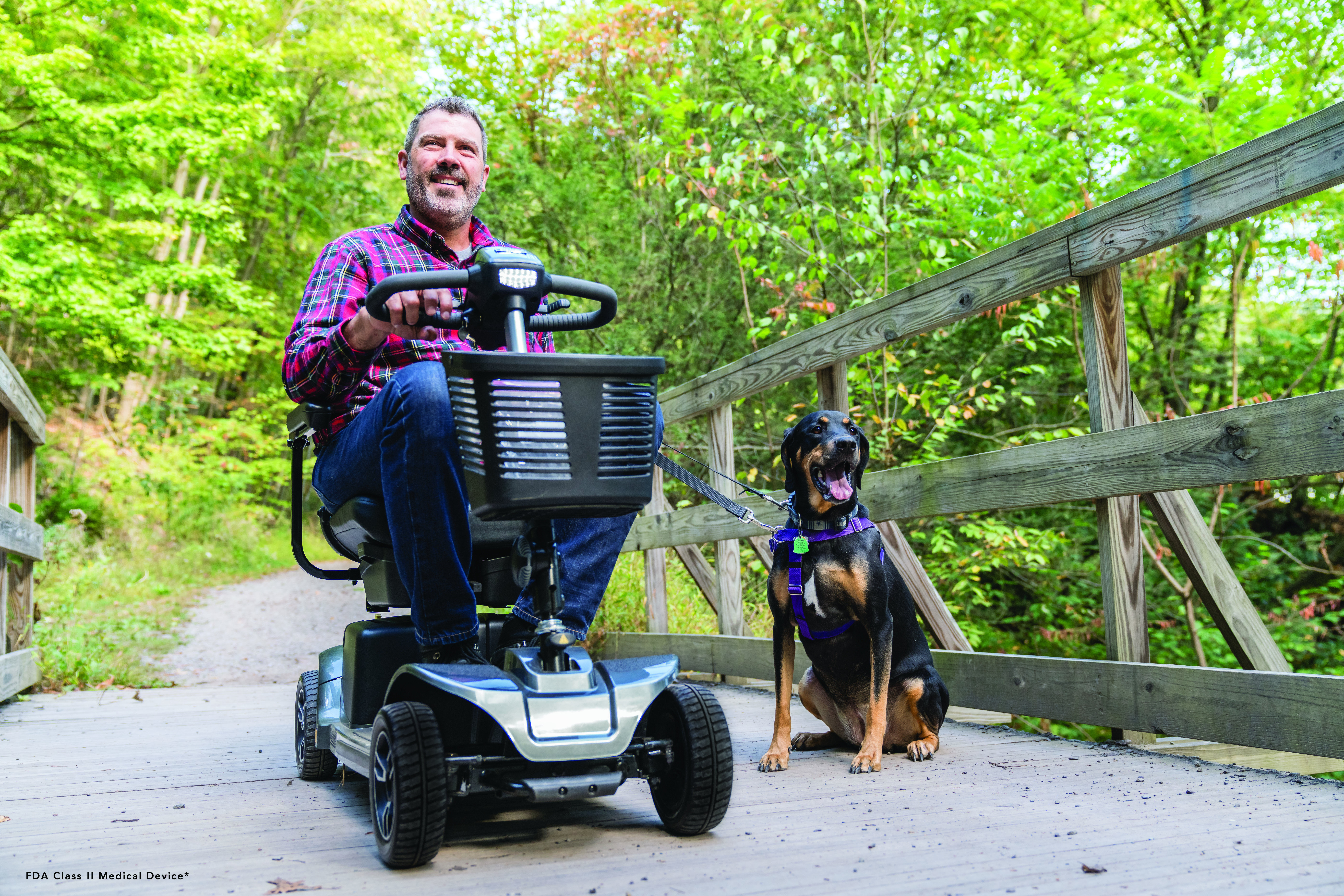A man walking a dog using his electric wheelchair.