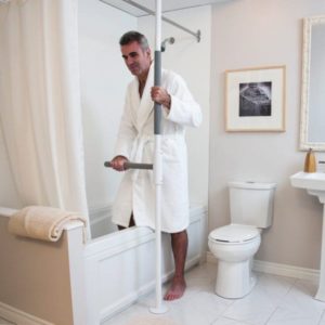 A man using a stabilizing bar to get into the shower.